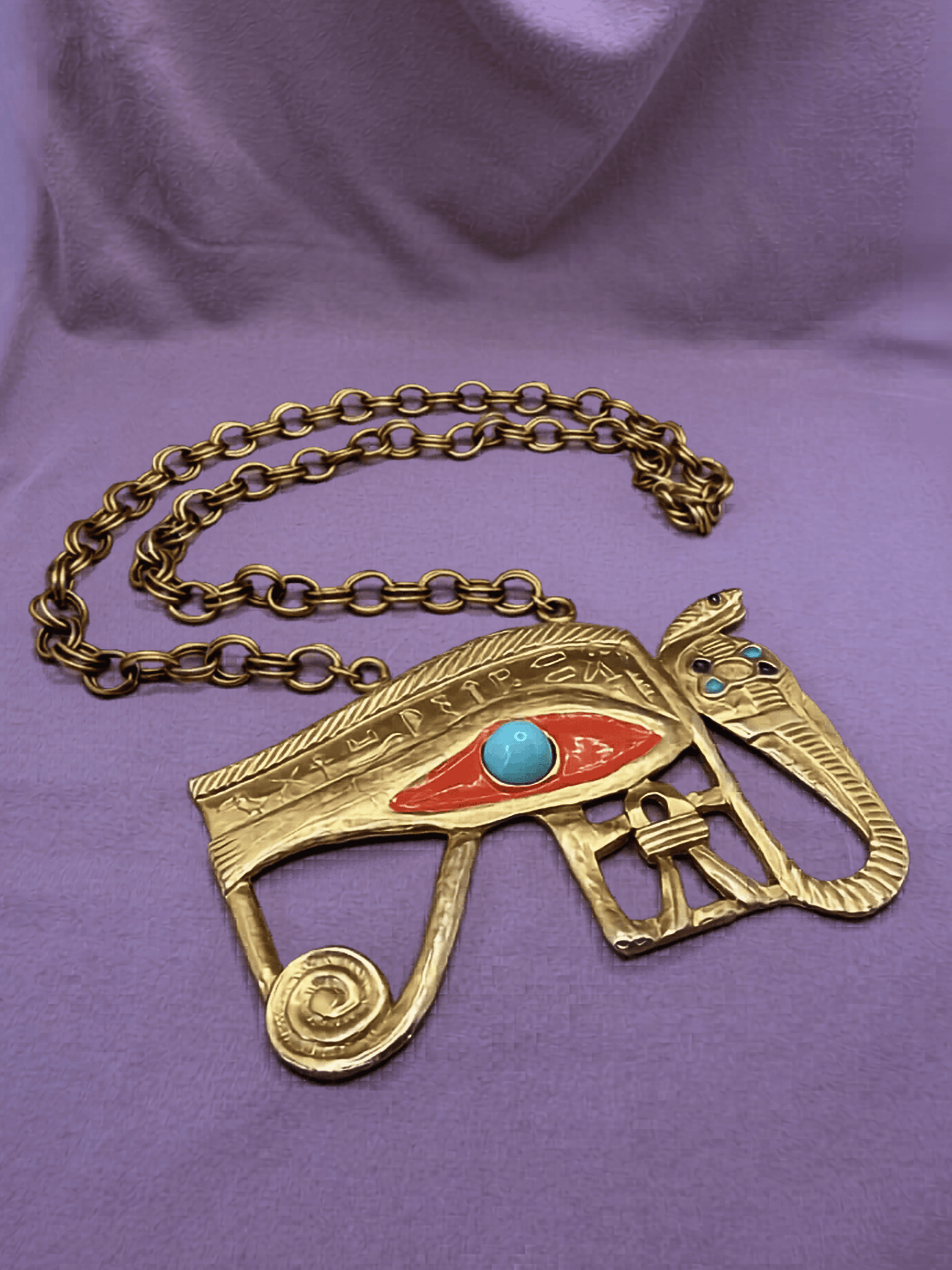 Gold eye of horus and cobra necklace on a purple background