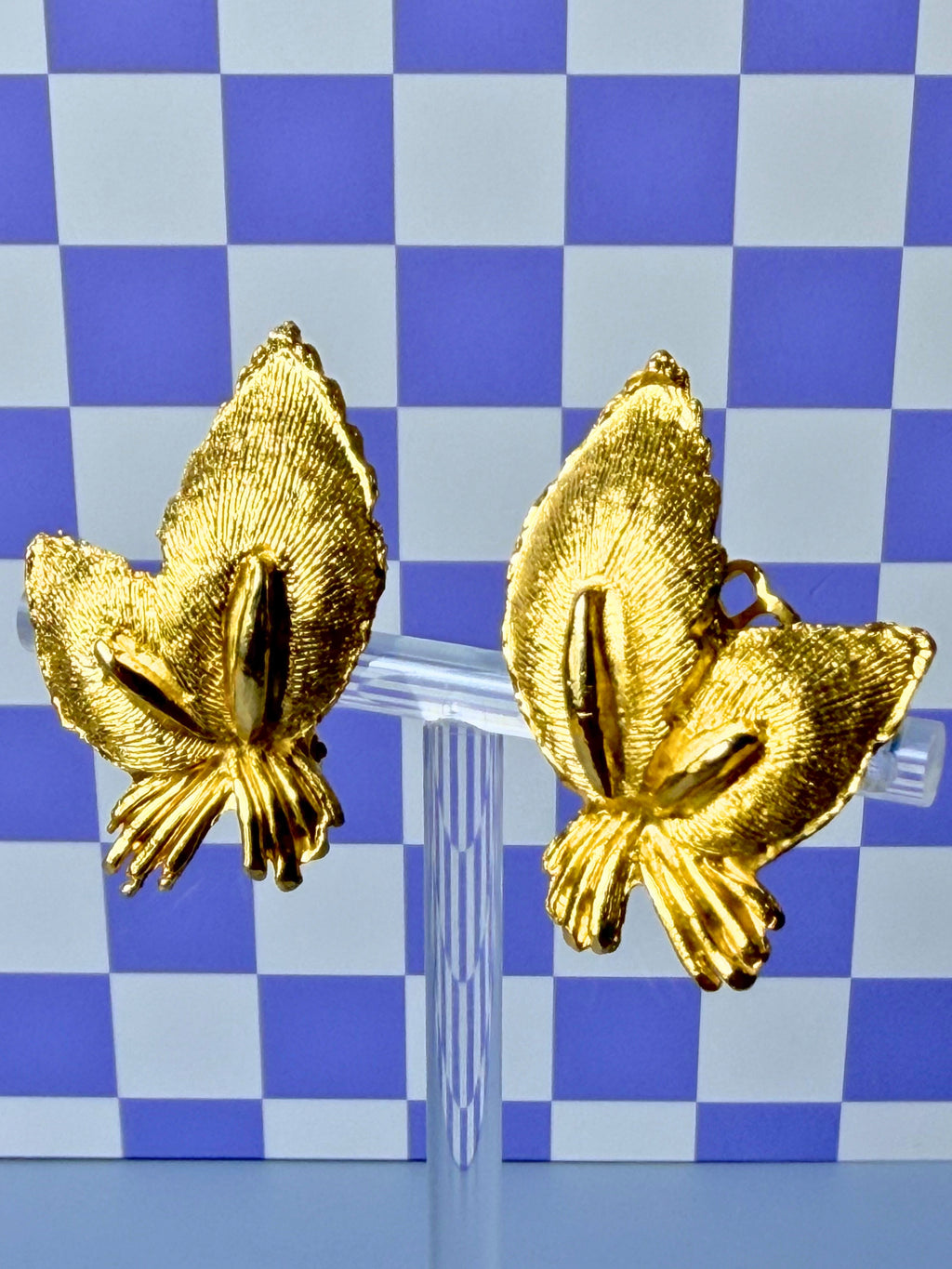 Gold leaf earrings on a blue and white checkered background