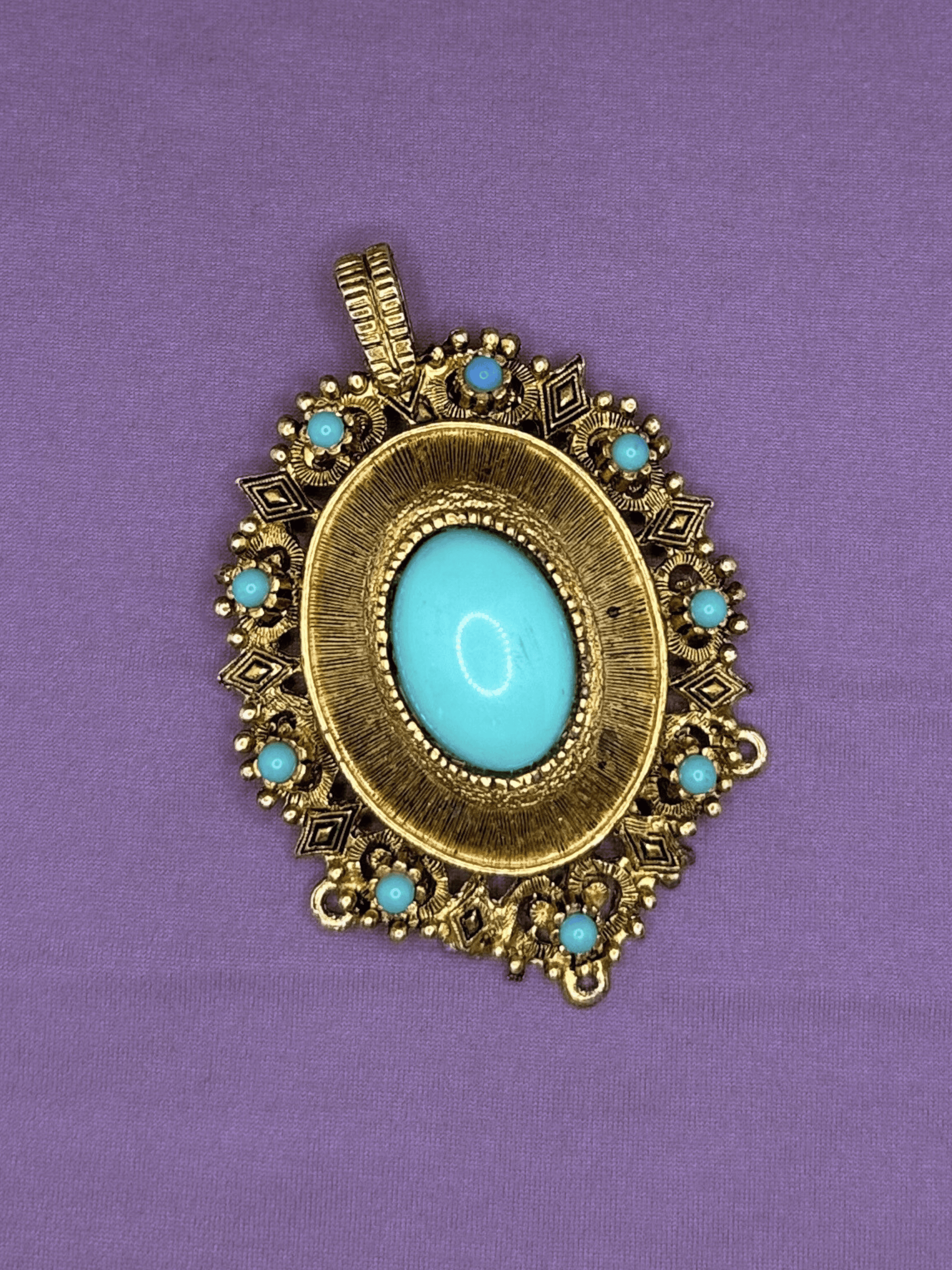 Decorative pendant with turquoise stones on a purple background