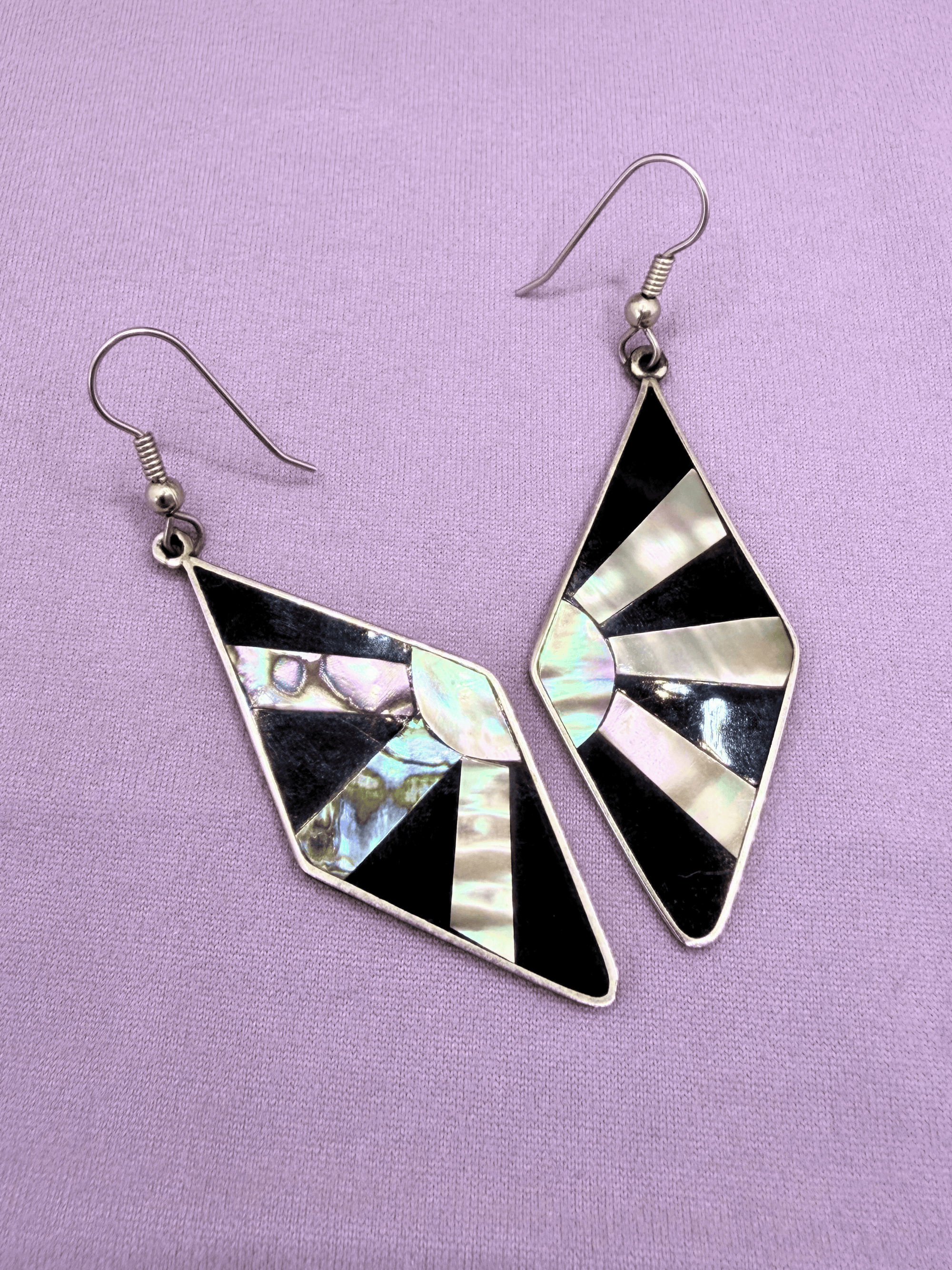 Geometric earrings with black and white design on a purple background