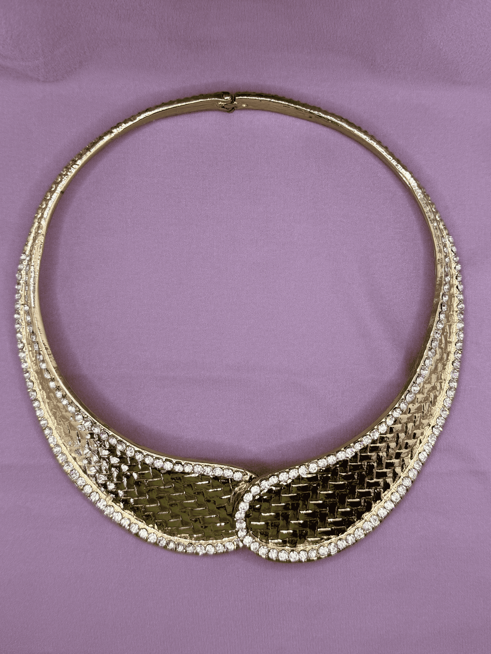 Gold necklace with a textured design on a purple background
