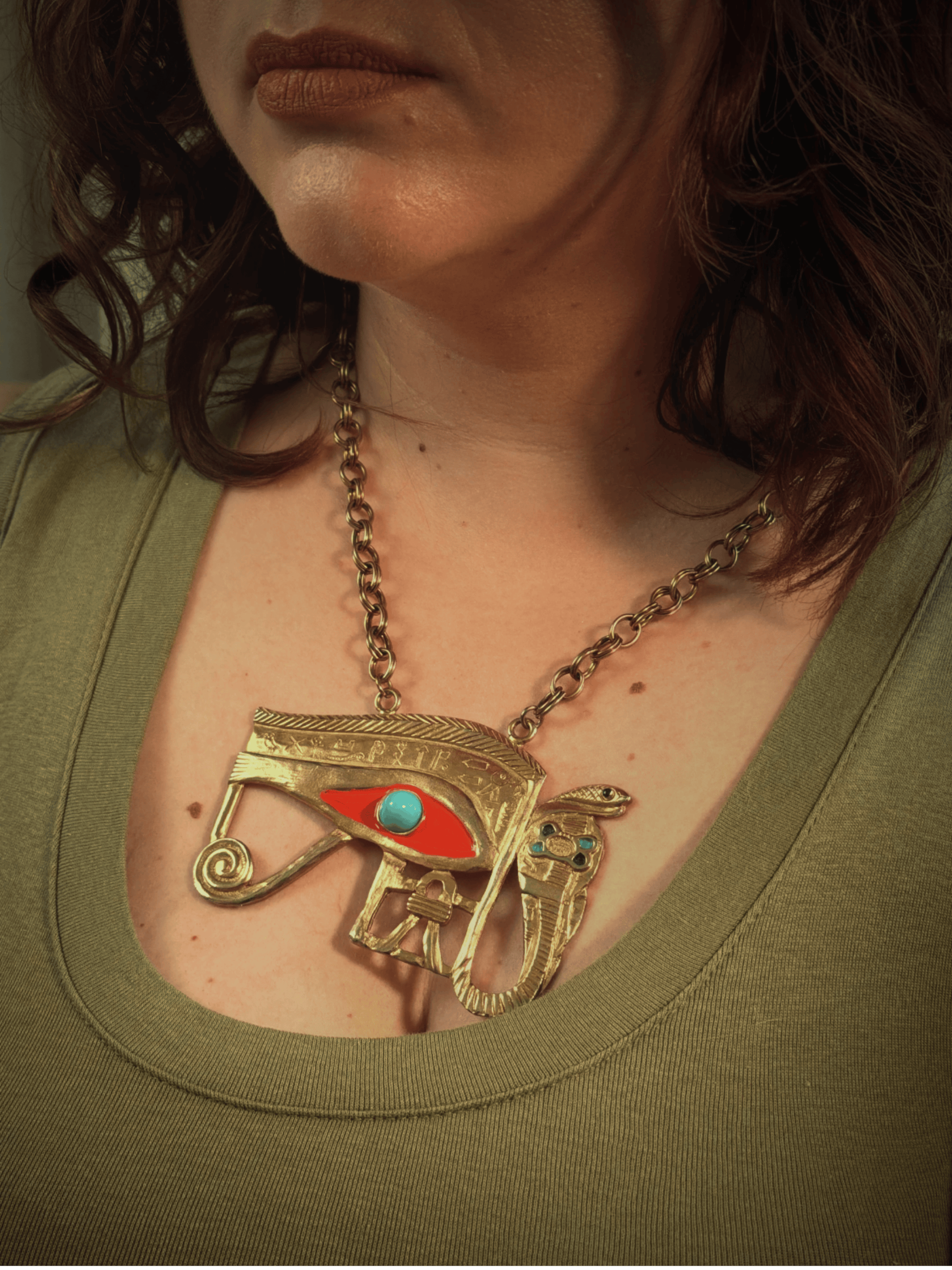 Close-up of a person wearing an ornate necklace with a lage eye of horus  pendant.