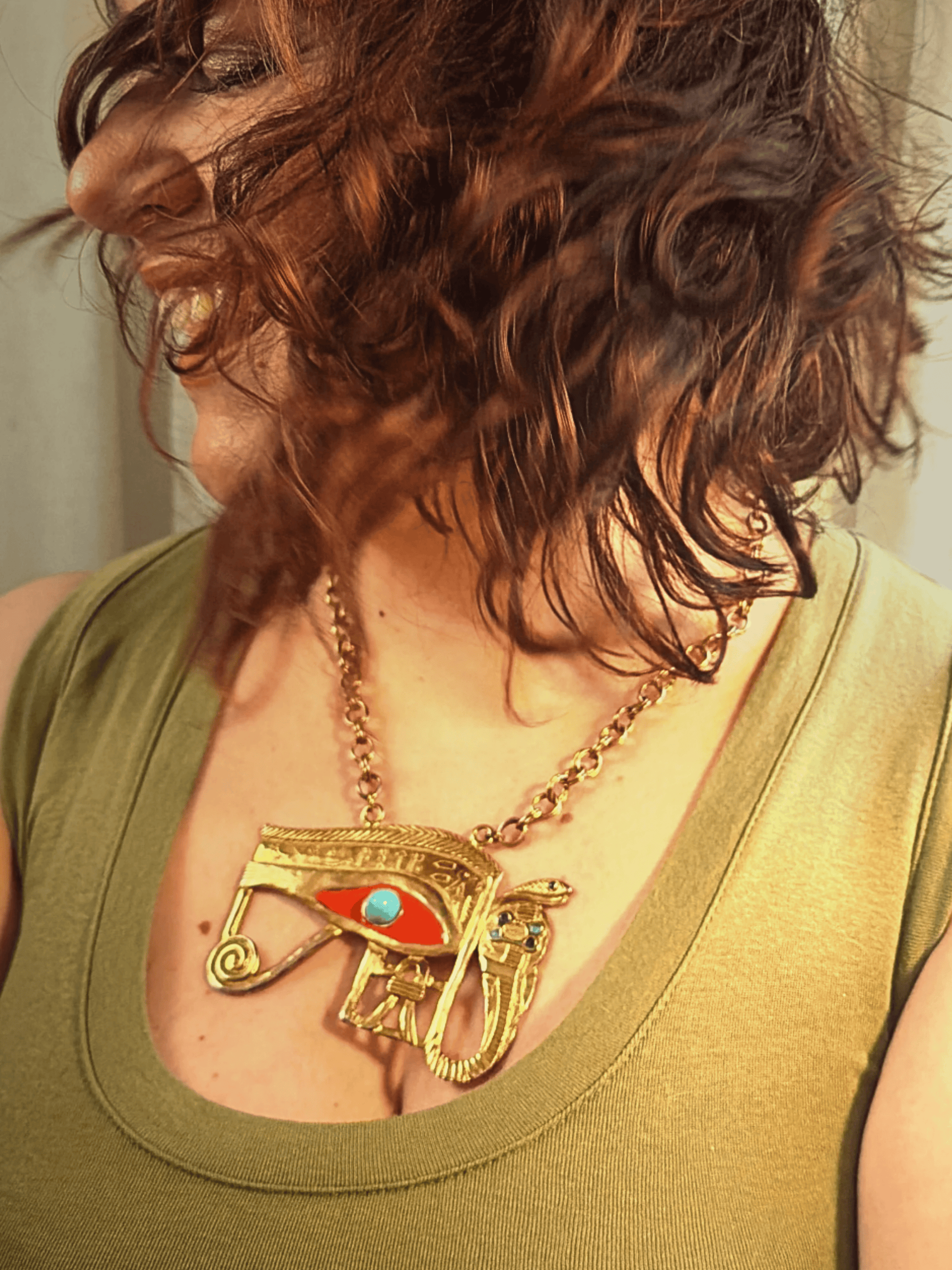 Person wearing a gold necklace with an eye of horus design