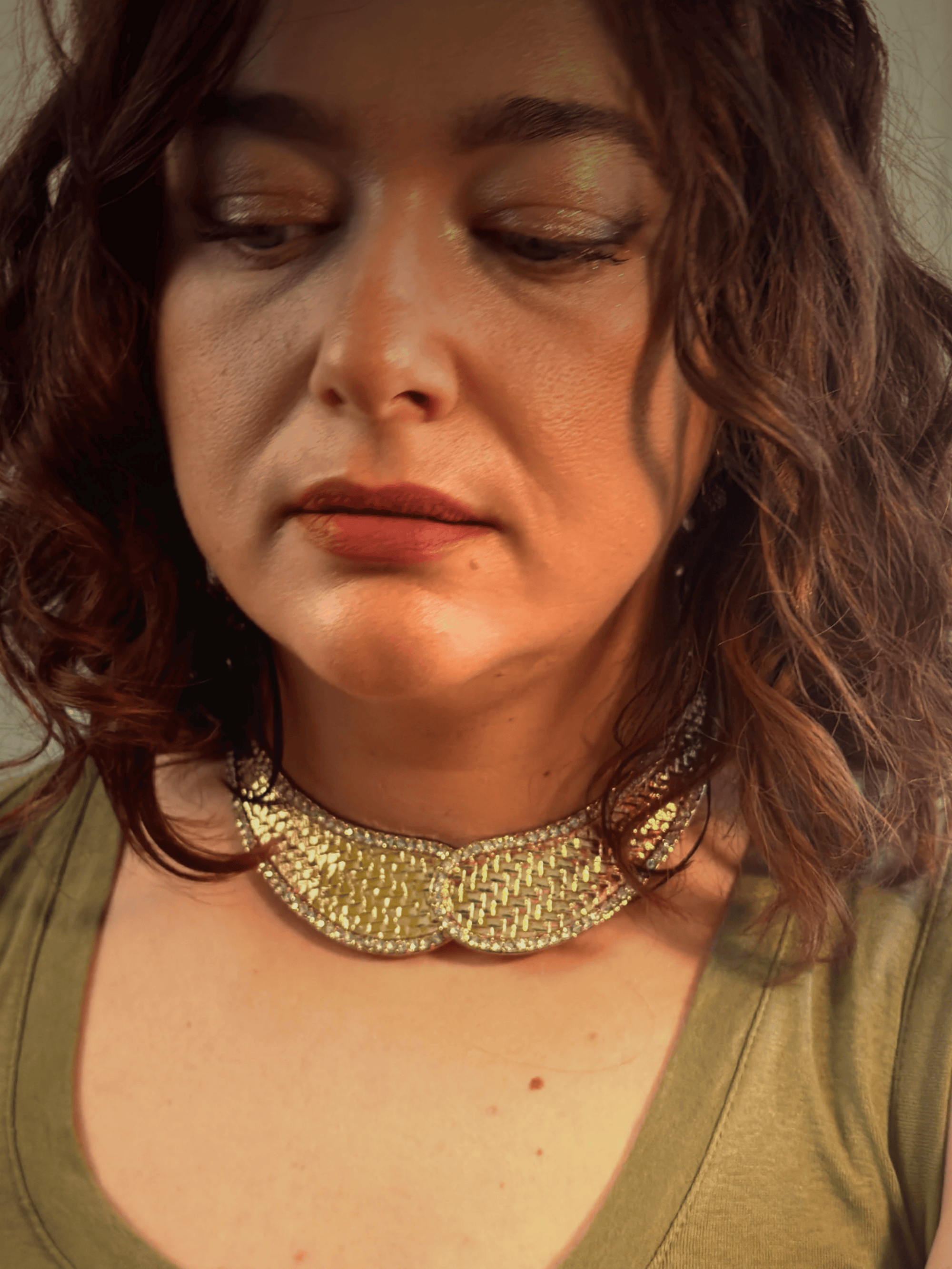 Woman wearing a gold necklace with a neutral background