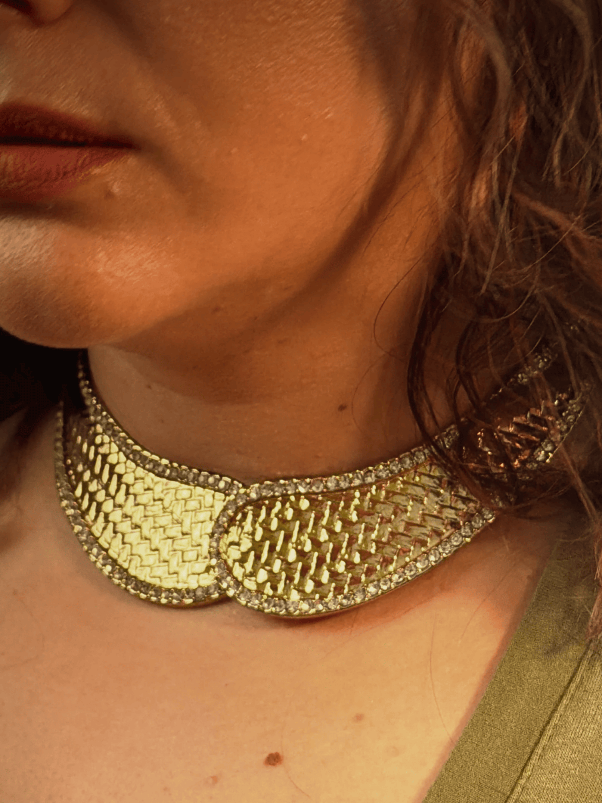 Close-up of a person wearing a gold necklace with a textured design.